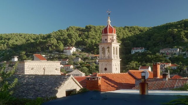 The ancient building of the parish church of Saint Jerome of Stridon in the port town of Pucisca (Puči&scaron;ća) on the island of Brac (Brač), Croatia. A bell tower with a clock on a stone church tower.