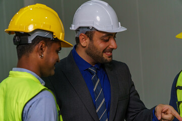 Construction project meeting with workers discussing plans in a modern facility during daylight hours