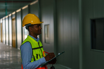 Construction site worker inspecting safety standards with a clipboard and hard hat at a facility