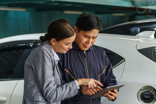 Technician discusses vehicle repairs with client inside an auto shop during the day