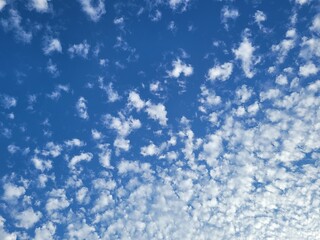 Blue sky full screen background with fluffy white cloudlets or cumulus cloud