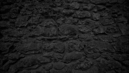 A black stone wall with a lot of rocks. wall is very dark and has a lot of texture background