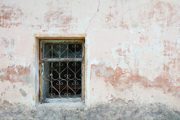 A window with a metal frame and a window screen. The wall is made of stone