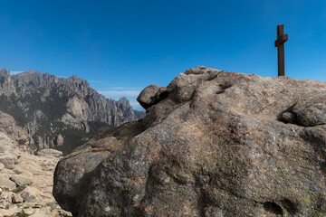 Gipfelkreuz im Bavella Massiv unter blauem Himmel, Korsika