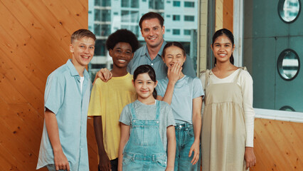 Happy teacher and diverse student standing while smilling to camera. Professional smart instructor with highschool children with mixed races in casual outfit pose at camera with cheerful. Edification.