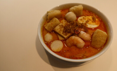 close up of Singaporean Malaysian soup laksa noodles with fishballs, tofu bean curd, prawns, shrimps and fish slice