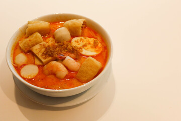 close up of Singaporean Malaysian soup laksa noodles with fishballs, tofu bean curd, prawns, shrimps and fish slice