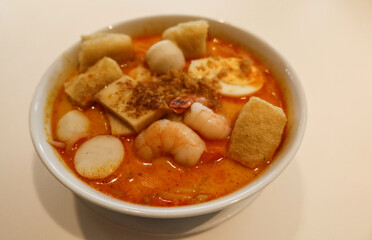 close up of Singaporean Malaysian soup laksa noodles with fishballs, tofu bean curd, prawns, shrimps and fish slice