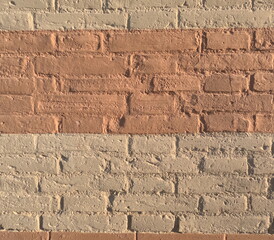 Brick wall with alternating painted horizontal bands in warm earthy tones. Textured masonry detail showing rough surfaces, weathered paint and tactile imperfections