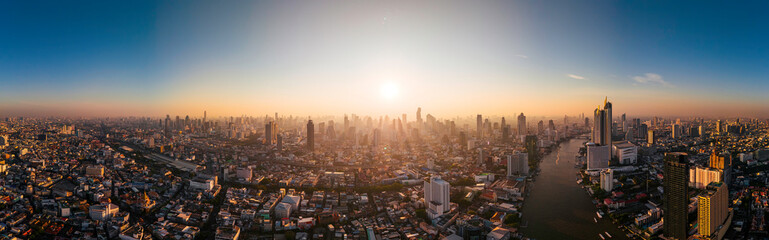 Fototapeta premium Aerial panorama of Bangkok city at amazing sunrise. The first sun rays shine through the tall buildings at dawn