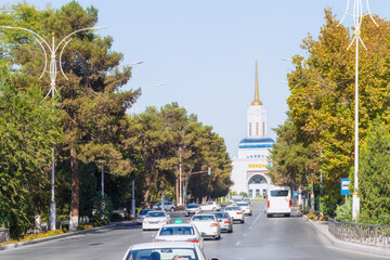 Road leading to a railway station in Ashgabat, Turkmenistan, lined with lush green trees,...