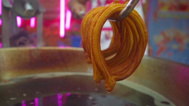 Close-up of golden churros freshly-cooked, showing their crispy outside and soft inside texture, ready to be covered in sugar and cinnamon. Hot frying highlights their perfect golden color.