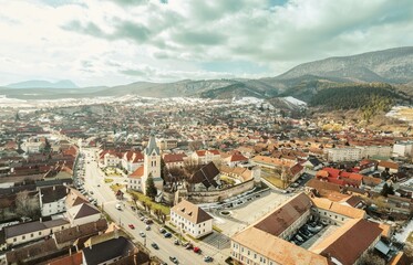 Capturing the enchanting aerial view of Rasnov and Piatra Craiului, showcasing the vibrant rooftops, historic buildings, and majestic mountains under a dramatic sky