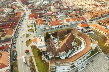Fototapeta premium Sweeping views showcase the charming architecture of Rasnov surrounded by picturesque snow-covered landscapes. The historical fortress stands proudly amid vibrant rooftops and serene mountains