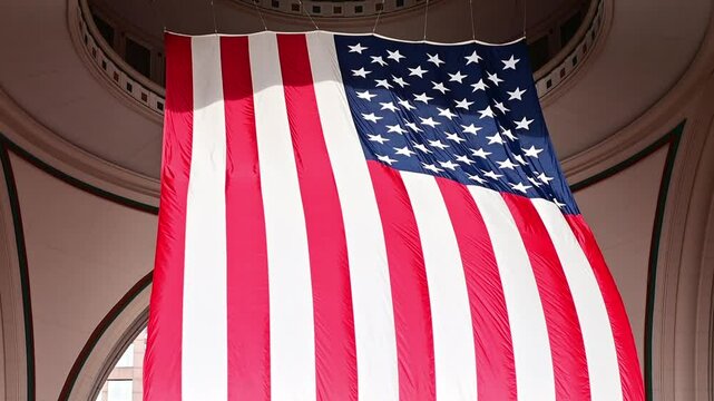 Huge American flag flying from the ceiling of a building in a slow motion video clip.
