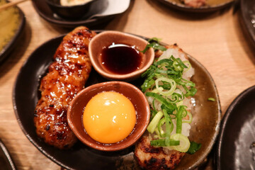 close up of Japanese minced chicken meat skewer with raw egg and soy sauce for dipping