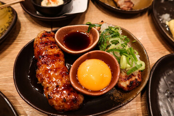 close up of Japanese minced chicken meat skewer with raw egg and soy sauce for dipping