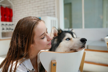 Smiling woman with her Siberian Husky puppy enjoying outdoor friendship and love