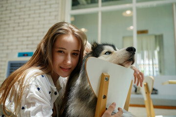 A woman with a dog smiling together in the park, showing happiness and friendship