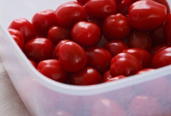 Red cherry tomatoes in a plastic container. Close-up.