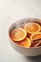 top-down view of steaming bowl of mulled wine garnished with orange slices and cinnamon sticks glowing under soft diffused