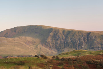 Lovely Autumn sunset landscape image looking towards Great Dodd from Castlerigg Stone Circle with soft pastel light