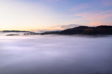 Beautiful atmospheric aerial drone landscape image of cloud inversion in Loughrigg valley in Lake District during Autumn