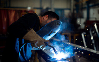 man who works in the metal industry welding with his protective equipment