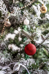 Vertical Christmas card - close-up of fir branches decorated with balloons, garlands, lights and Christmas tree toys.