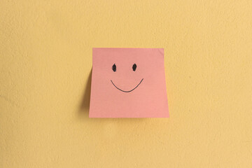 positive attitude concept with sticky notes with happy face.one smiling; Concept with sticky notes, pink note on yellow background. 