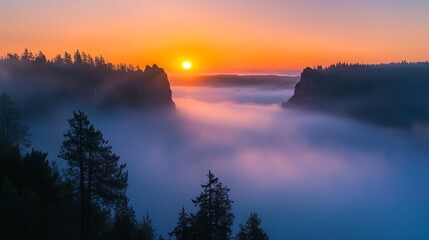 Obraz premium Scenic sunrise views, the sun emerging over mist-covered mountains, creating a dramatic play of light and shadows