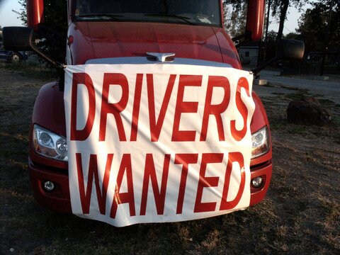 Drivers Wanted sign on front of tractor, at company yard.
