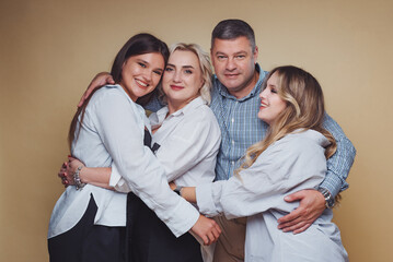 Group of four people posing together in casual attire with smiles in a studio setting