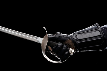 A gloved hand firmly grips the hilt of a sabre, highlighting strength and readiness. The dark...