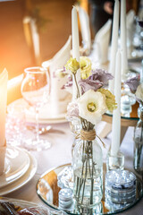 Wedding table decoration with flowers and candles. The elegant wedding table for guests. Stylish table set for wedding dinner