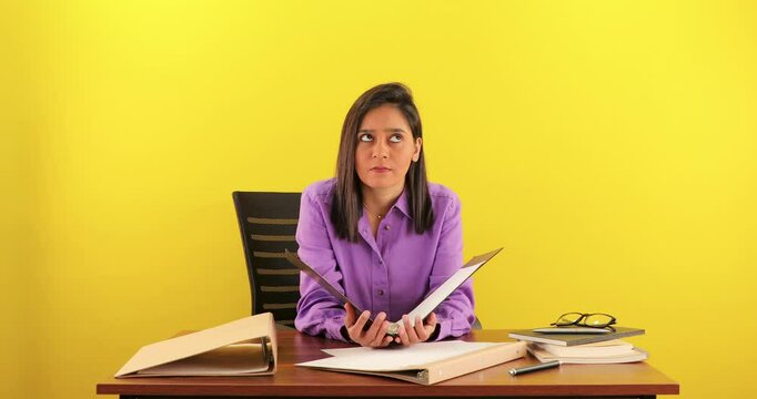 Confused South Asian young Indian business entrepreneur woman reading a file, pondering a decision