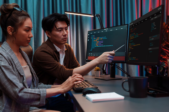 IT developers discussing with point to intelligent website development coder system running data online two screens information technology at neon light room at modern office. Infobahn.