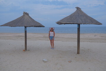 woman on the beach beach chairs and umbrellas on beach a woman is walking on the sea and beach, you can see the sedentary wind