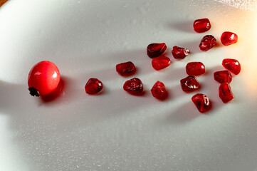 Symbolic Journey of Pomegranate Seeds Towards New Life. Scattered pomegranate seeds on a white...