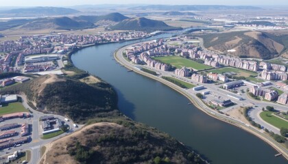 Fototapeta premium Aerial View of River Meandering Through a City Nestled in Rolling Hills