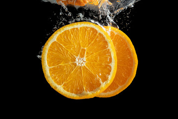 Fresh sliced orange fruit in water splash isolated on black background. Minimal food concept.