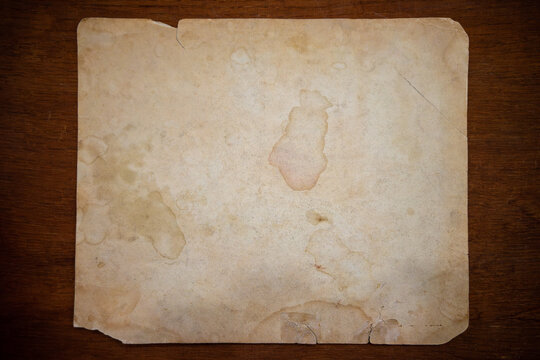 The photo is a piece of old paper with several stains and signs of wear.Vintage paper background for text.An old manuscript on the table.