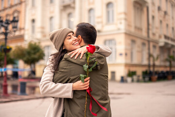 A Caucasian man surprises his happy female partner with a rose on International Women’s Day. Both...