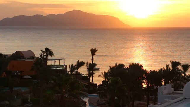 Dramatic morning sky with the sun rays crossing the clouds. Harmony of seclusion and meditation near the beautiful sea waves. The golden or blue hour of the sunrise or sunset. Hotel resort Egypt