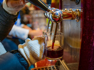 woman in the bar pours mulled wine into the glass. close - up.