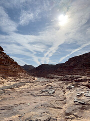 Red sandstone formations in the Red Canyon of the Sinai, Egypt. The image showcases rugged rock textures, desert sand, blue sky, highlighting the natural beauty and geological features of landscape.