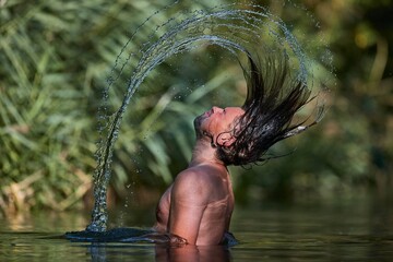 Man whipping wet hair in the lake