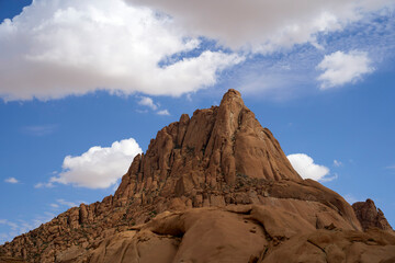 Fototapeta premium View looking up at the peak of Spitzkoppe in the desert of western Namibia with clouds up above
