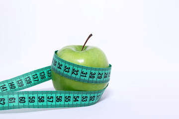 Measuring tape wrapped around green apple. Slimming and healthy lifestyle concept.
