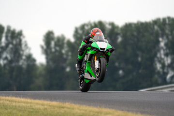 Rider on a green sport bike doing wheelie